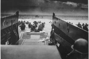 U.S. Soldiers disembark a landing craft under heavy fire off the coast of Normandy, France, June 6, 1944. (Photo Credit: National Archives U.S. Coast Guard Collection)